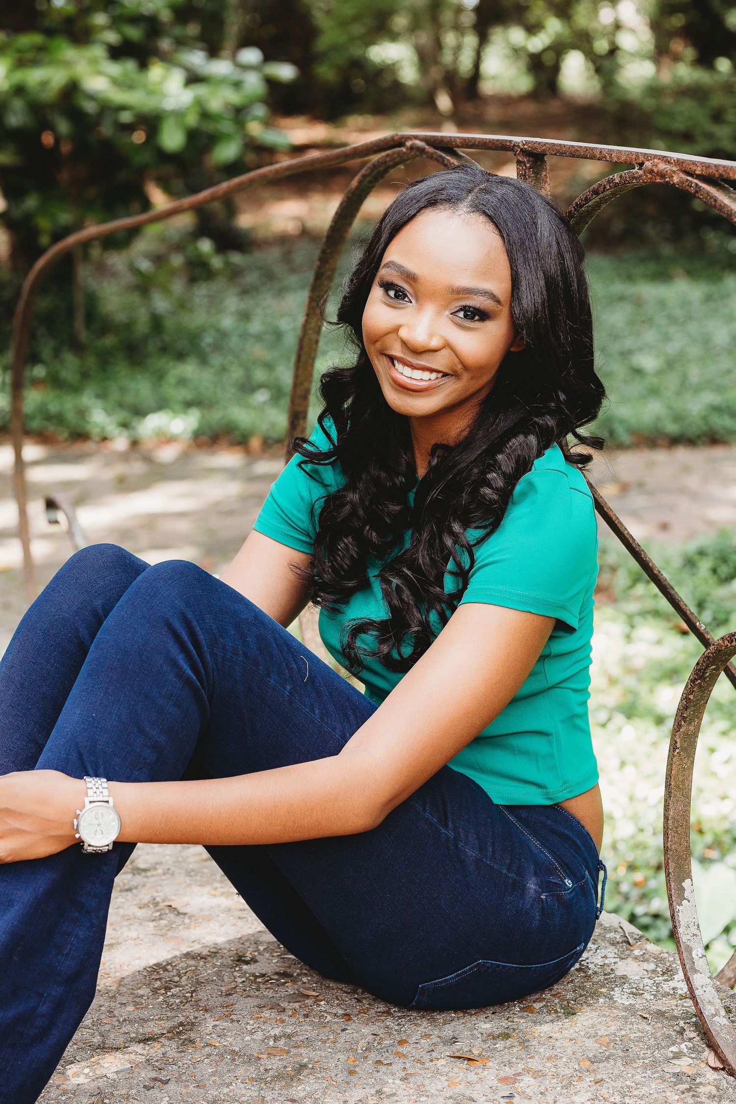 A casual outdoor photoshoot in a park setting featuring a teal shirt and dark jeans outfit.