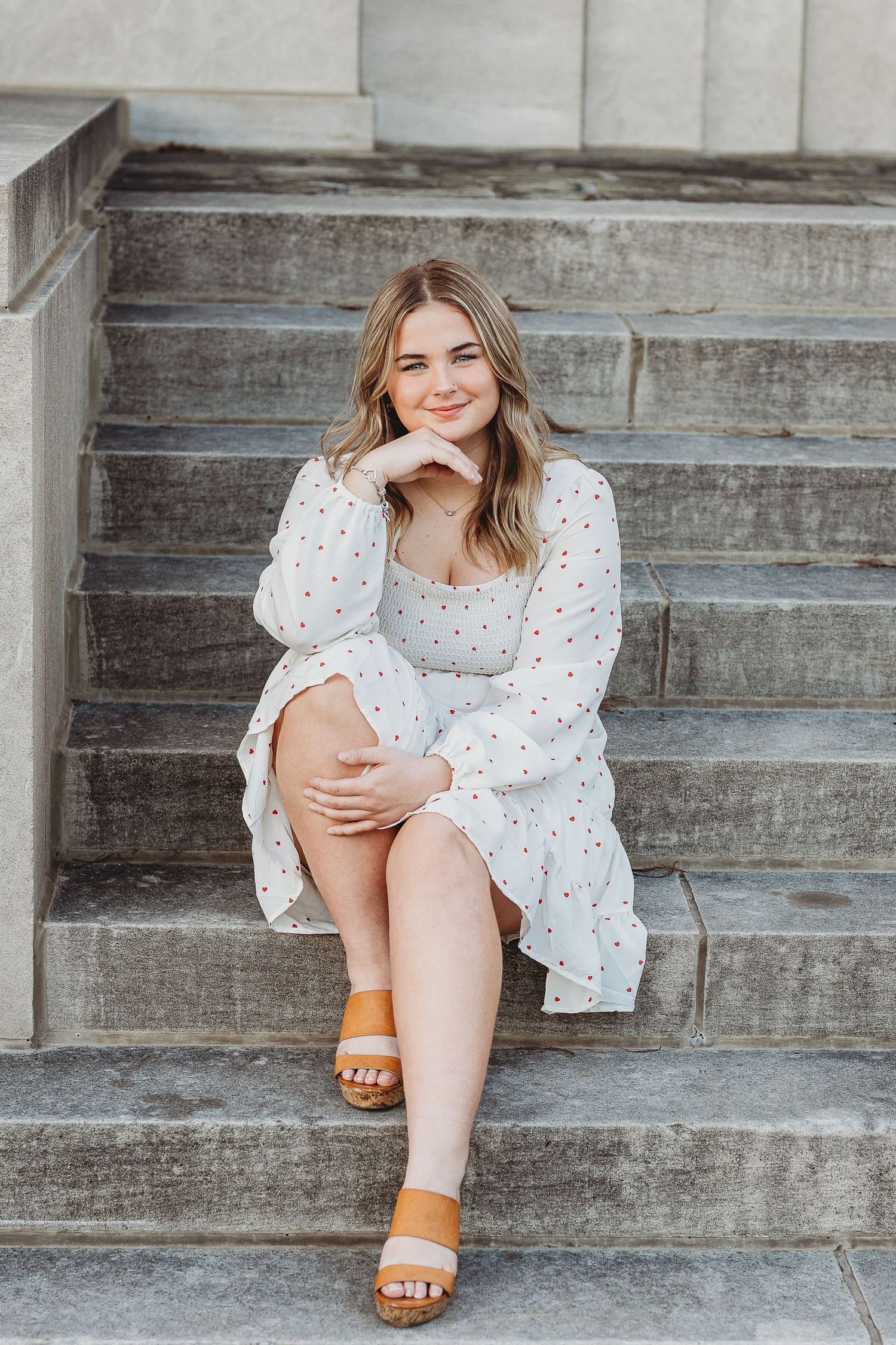 Casual summer style featuring white puff sleeve dress and orange sandals on steps.