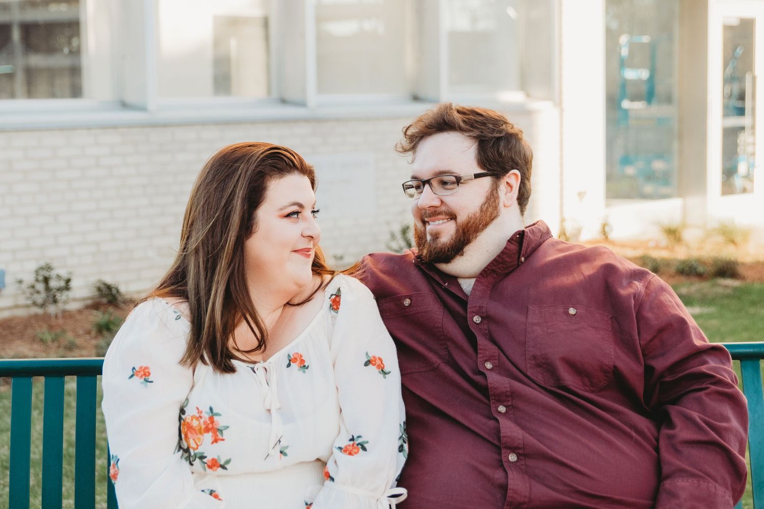 A couple in casual attire shares affectionate moments against a brick wall background.