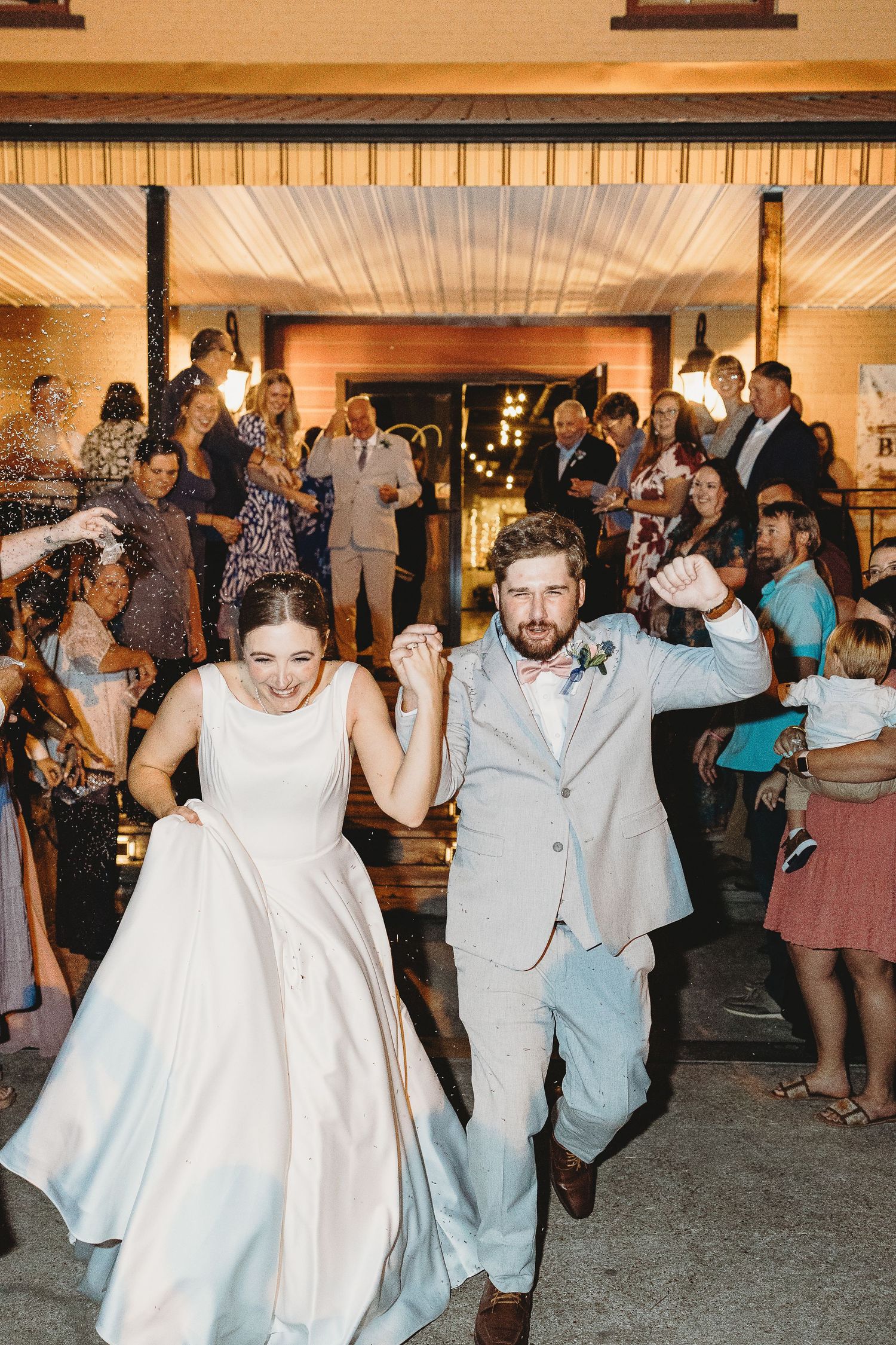 Newlyweds celebrate with joyful dance moves during their wedding reception exit.