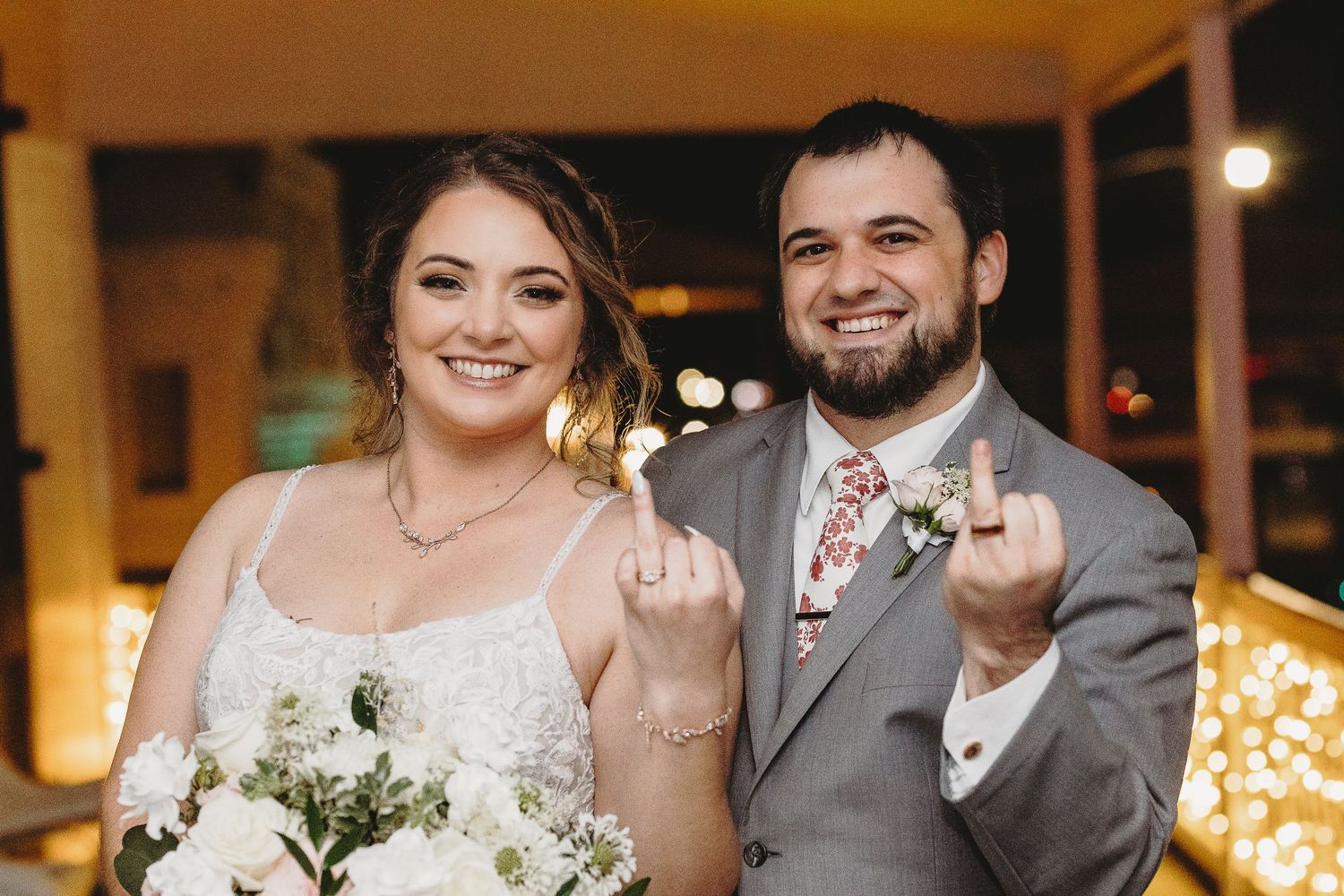 Wedding party members celebrate with joyful expressions in a warmly lit indoor venue.