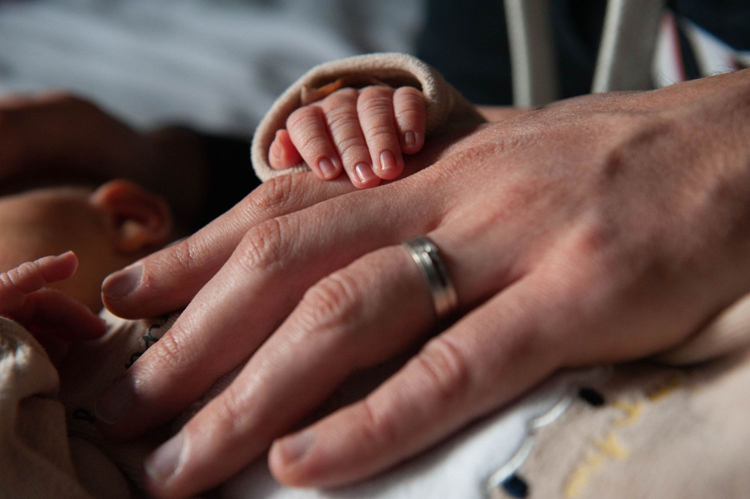 Main de bébé posée sur celle de son papa, symbole de tendresse et de lien familial, capturé par Vincent Bourdeix photographe portrait à Lyon