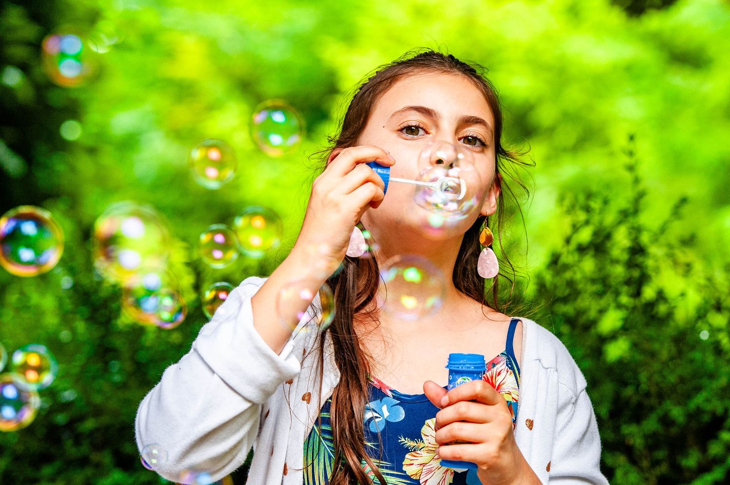 Portrait en couleur d'une enfant soufflant des bulles dans l’Ouest lyonnais. Photographie de portrait familial authentique.