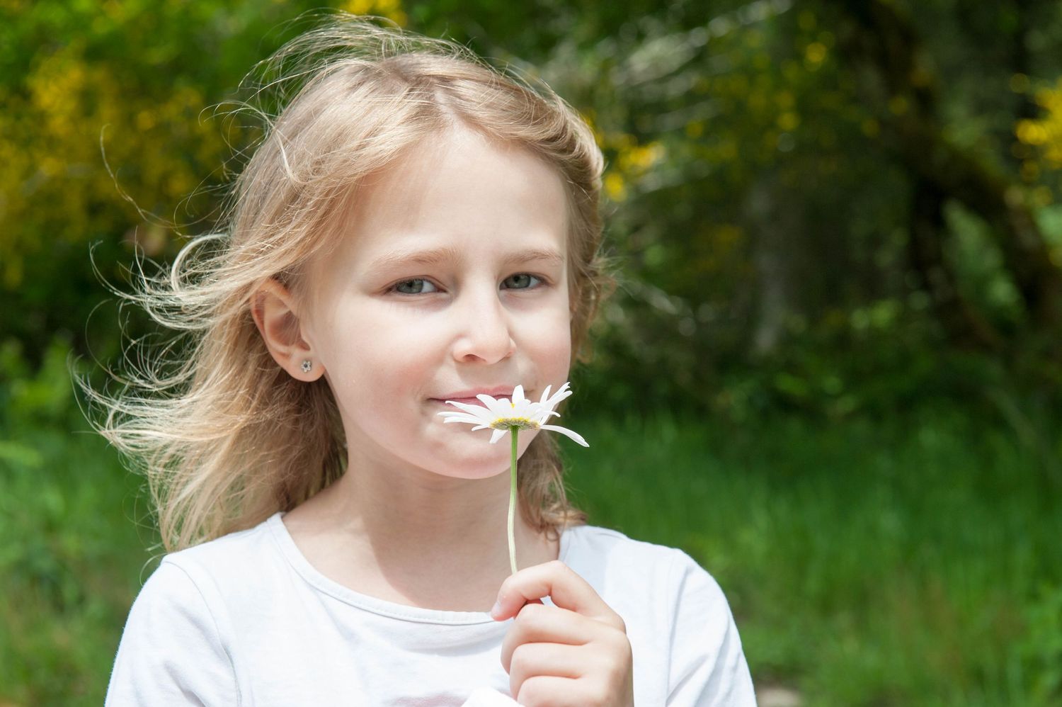 Portrait délicat d’une fillette tenant une fleur, capturé dans une lumière douce par Vincent Bourdeix, photographe lifestyle en région lyonn