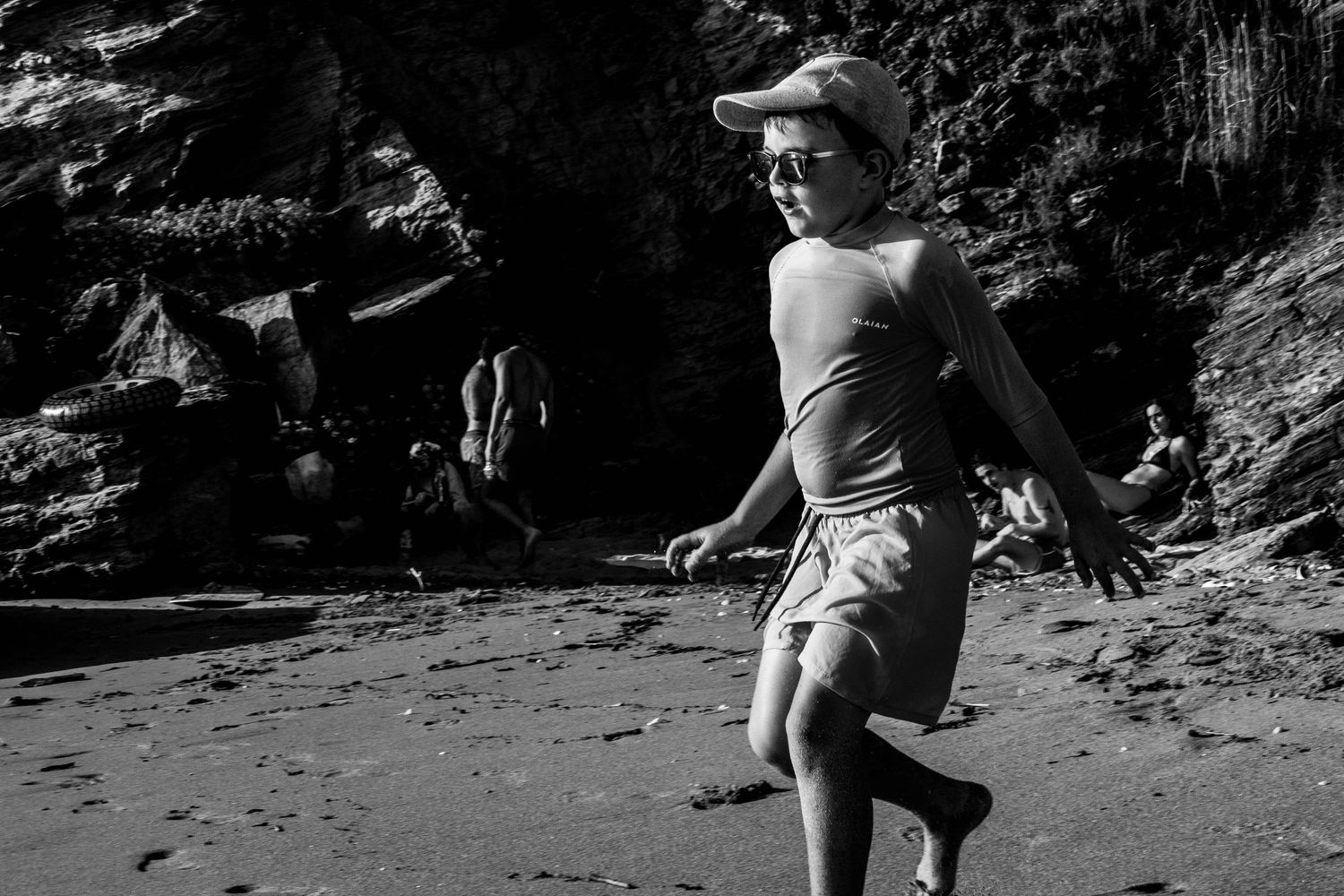 Photographie en noir et blanc d’un enfant courant sur la plage, style documentaire naturel. Photographe portrait Ouest lyonnais.