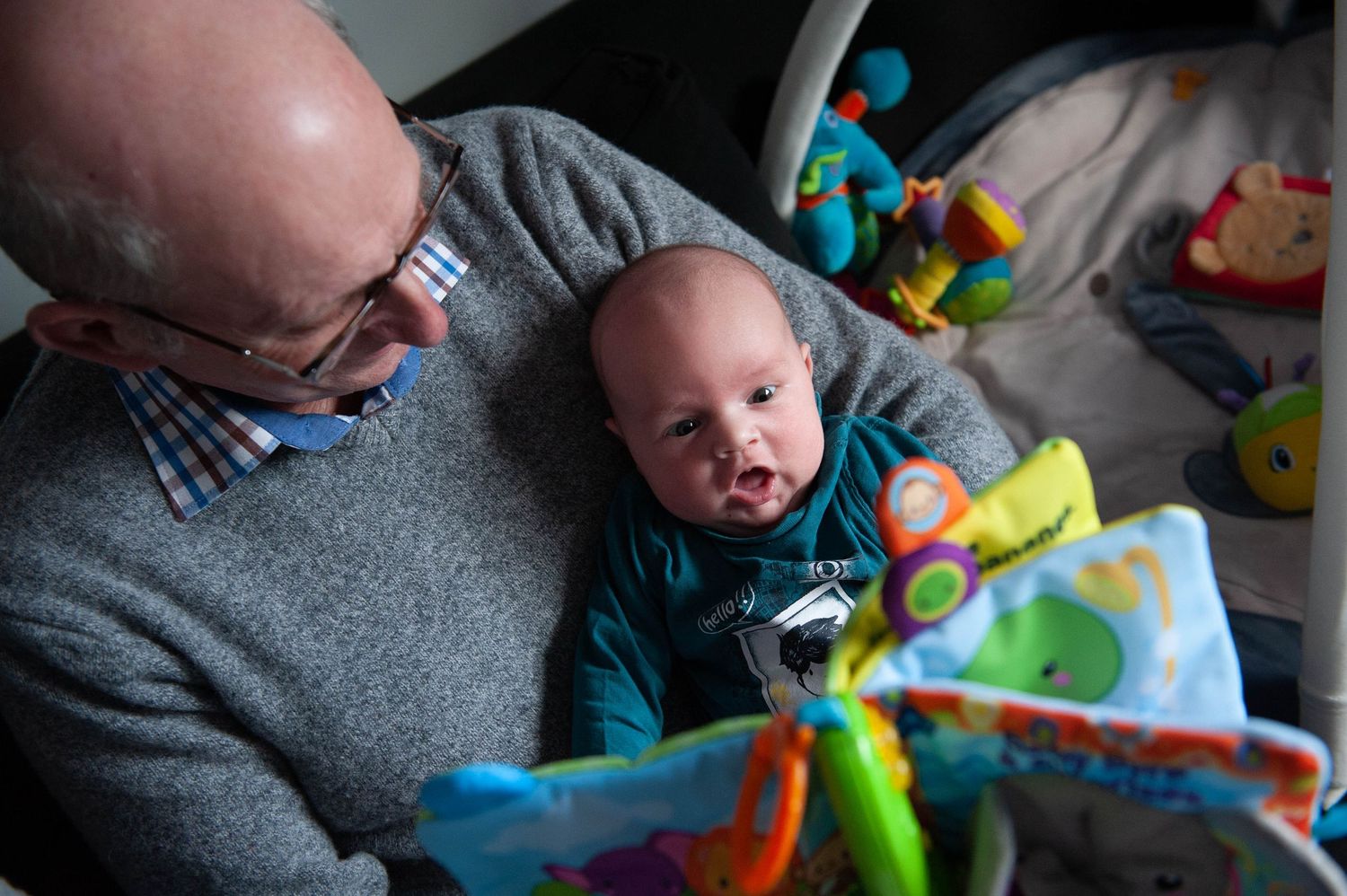 Portrait d’un bébé découvrant les couleurs dans un livre, partagé avec son papy. Un instant complice capturé dans l’Ouest lyonnais.