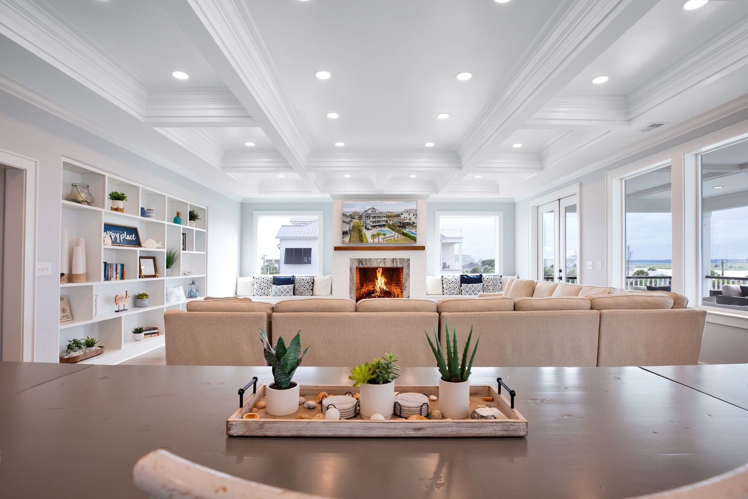 Elegant living room with coffered ceiling, fireplace, built-in shelves, and ocean views.