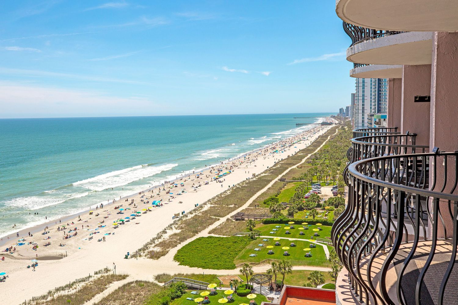 Stunning high-rise balcony view of a wide sandy beach and turquoise ocean coastline at Myrtle Beach, SC.
