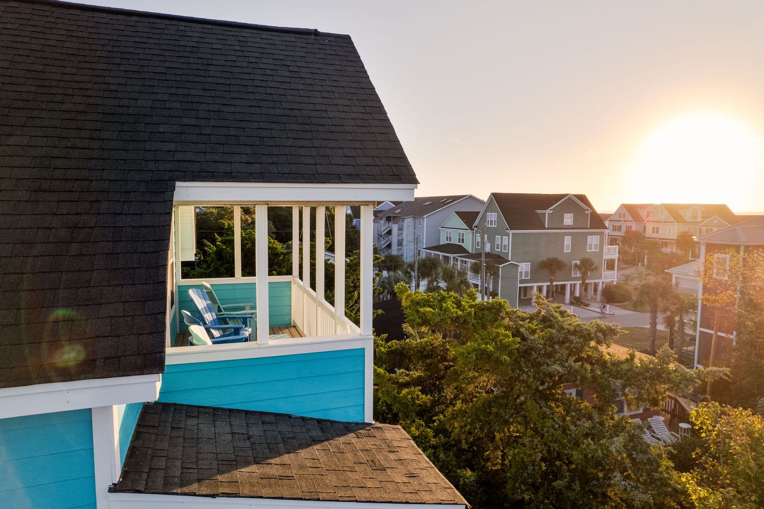 Sunset view from a balcony of a turquoise beach house overlooking a charming coastal neighborhood of Surfside Beach SC.