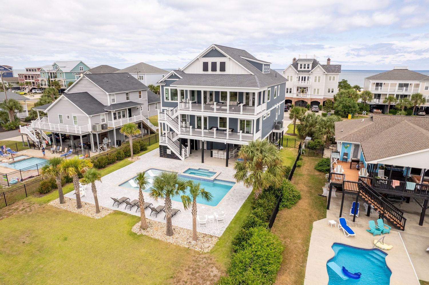 Aerial view of large multi-level beach house with private pool, and palm trees. Custom beach homes in Murrells Inlet, SC