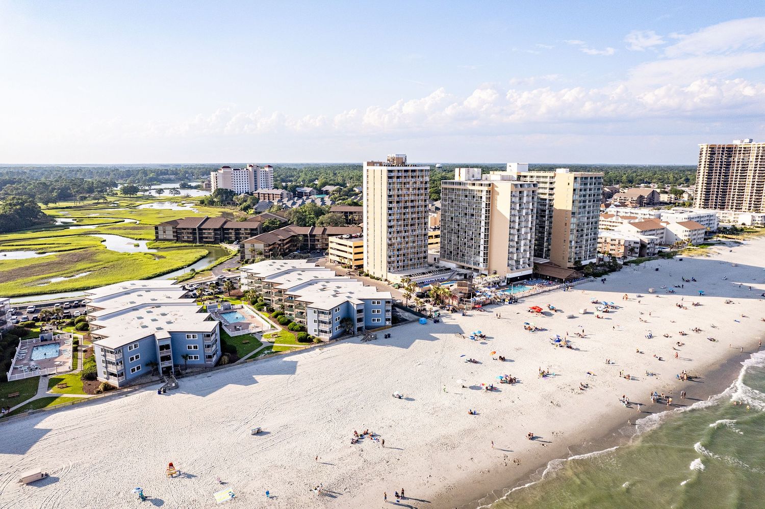 Aerial view of beachfront condominiums in Myrtle Beach with swimmers and sunbathers enjoying the shoreline, next to Ocean Annie's Beach Bar