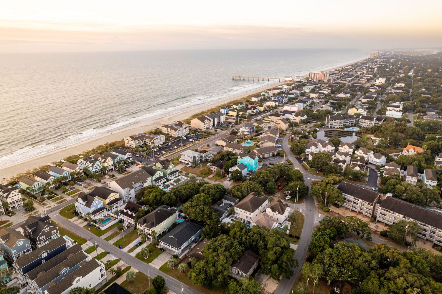 Aerial panoramic view of Surfside Beach with ocean shoreline and Surfside Beach Fishing Pier at sunrise.