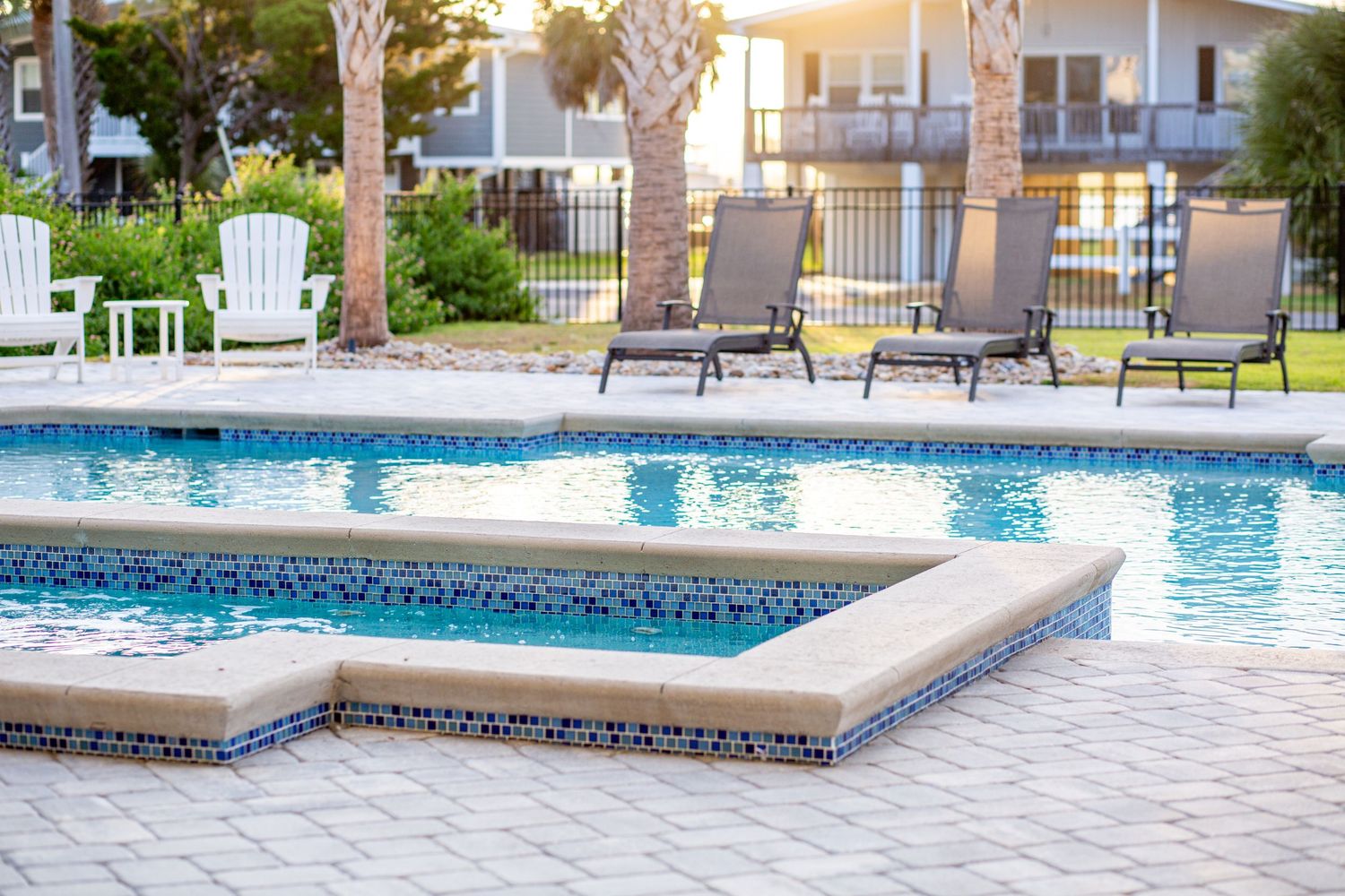Luxury outdoor pool at sunset featuring mosaic tile details, palm trees, and lounge chairs on a paved patio. Murrells Inlet SC Photography