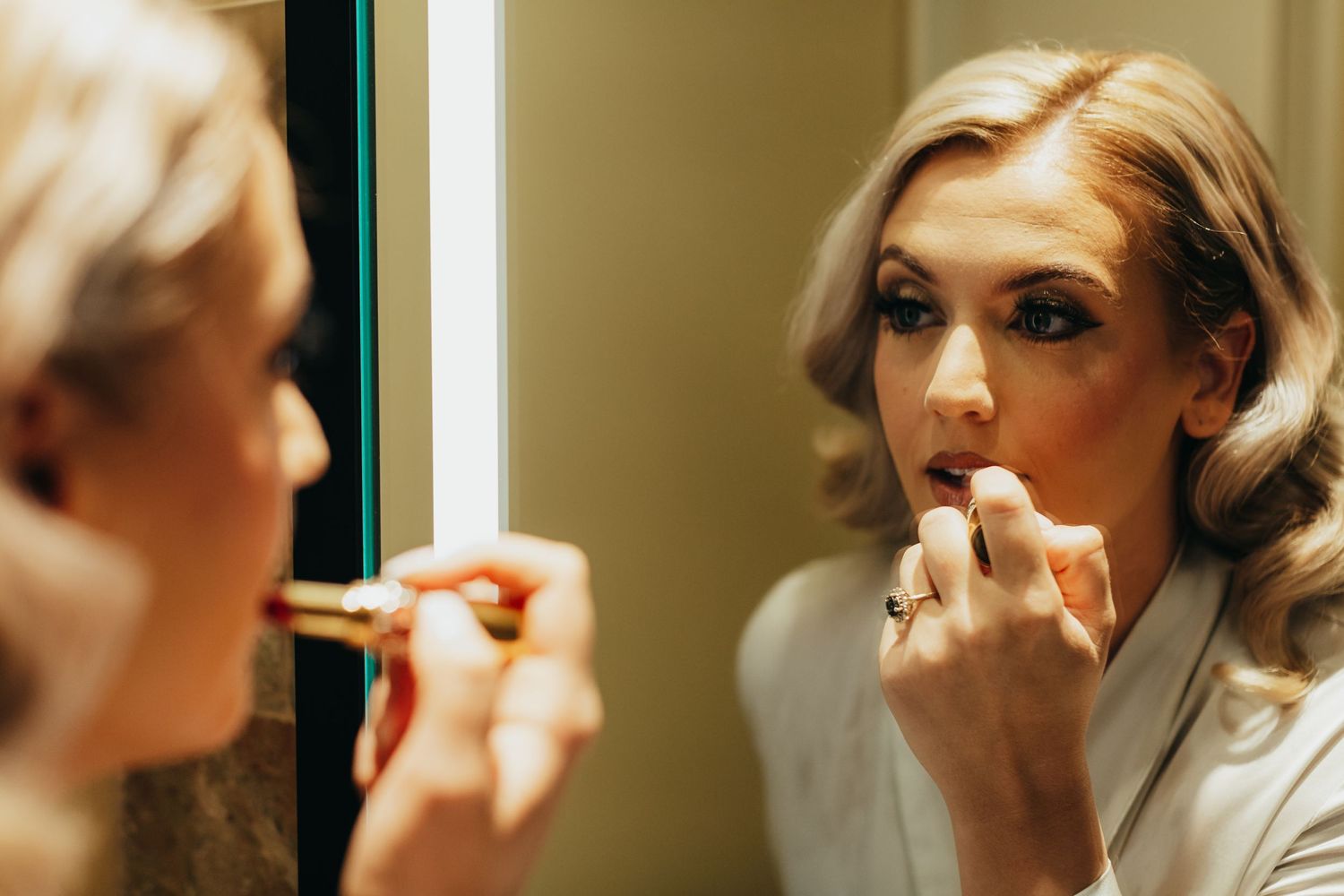 Close up of makeup application with brushes and cosmetics in warm lighting.