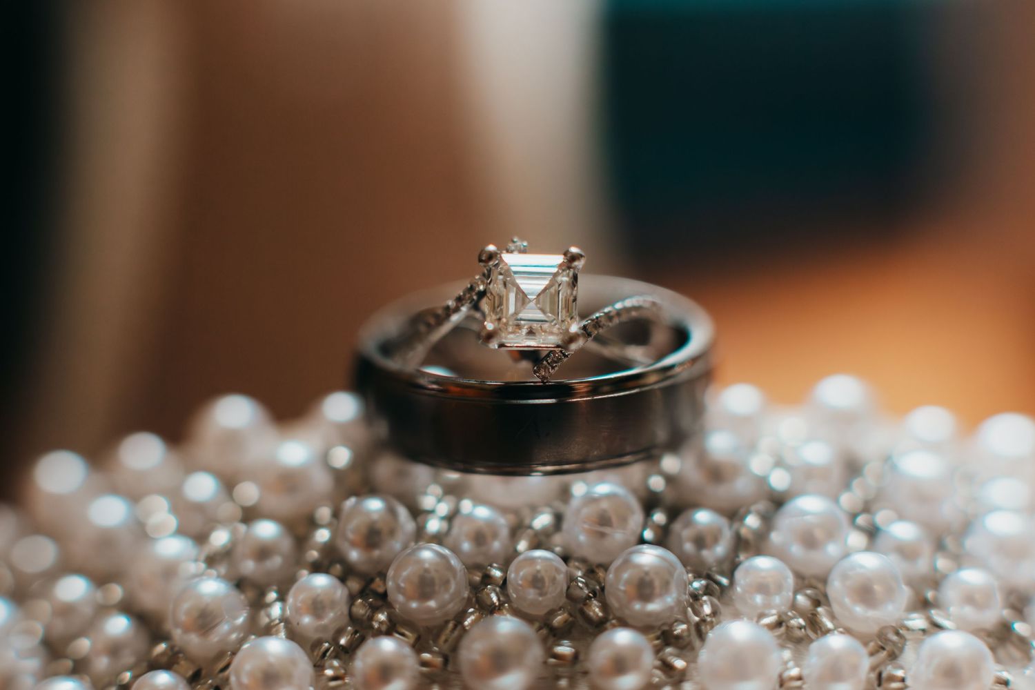 Diamond engagement ring displayed on pearls with shallow depth of field.