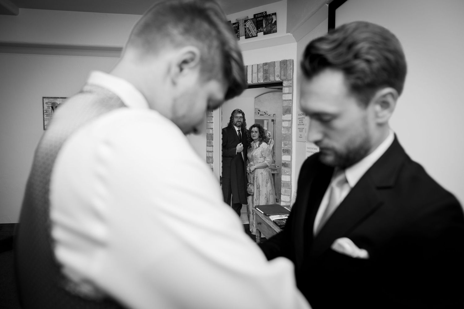 Two people in formal attire getting ready in a black and white candid moment.