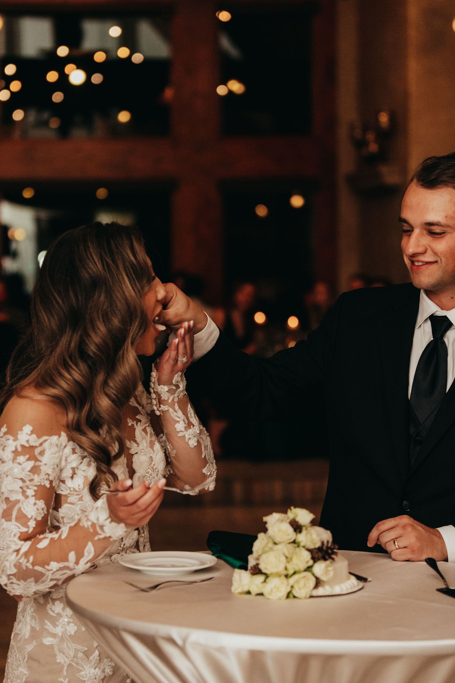 Candid reception moment of couple sharing dessert at their wedding table.
