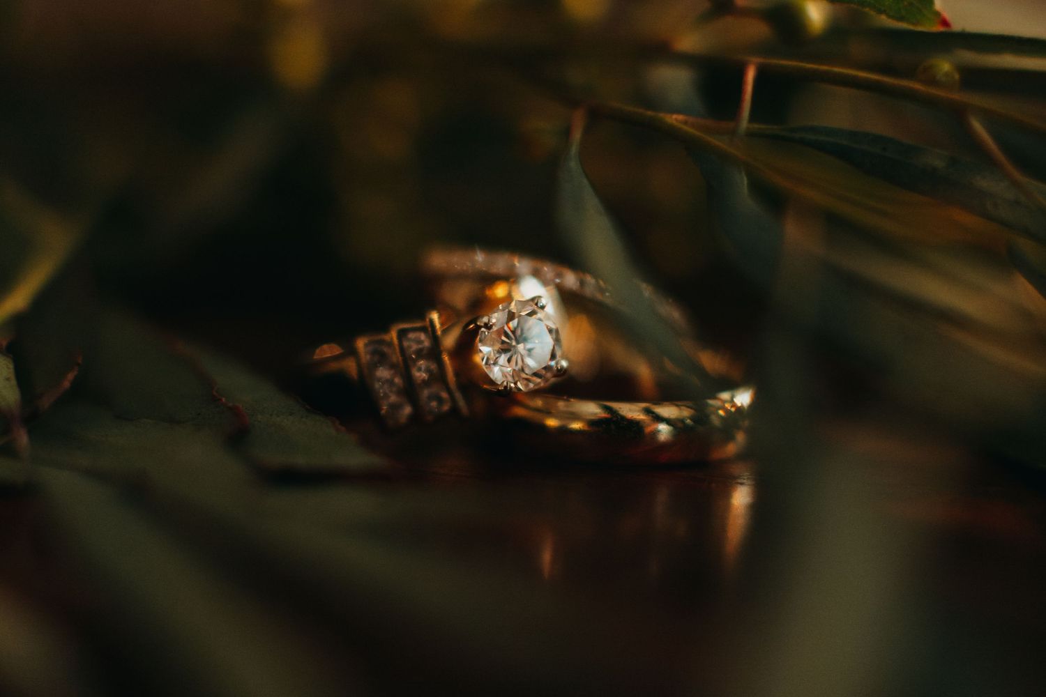 Wedding rings with diamond solitaire captured in dramatic macro shot.