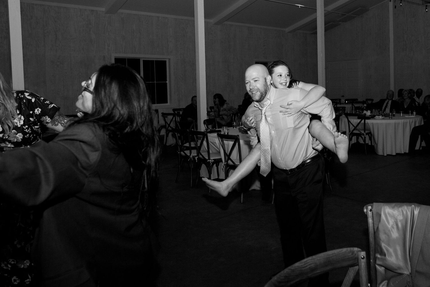 Wedding guests dance energetically in black and white on the reception dance floor.