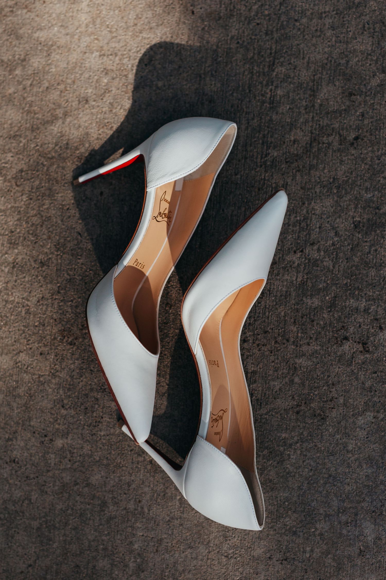 Elegant white leather bridal heels with pointed toes on dark background.