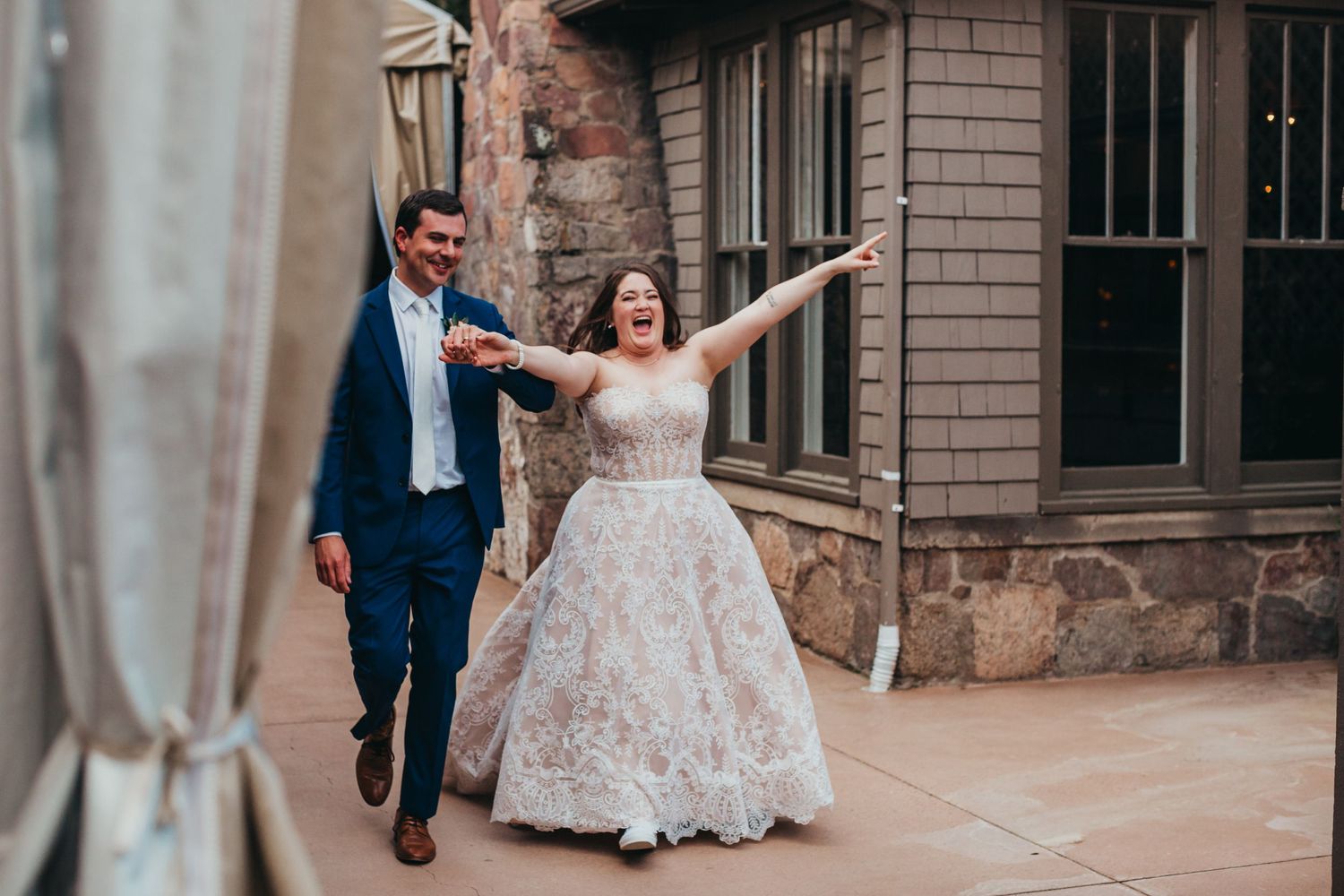 Joyful couple celebrates their wedding day running together down a scenic walkway.