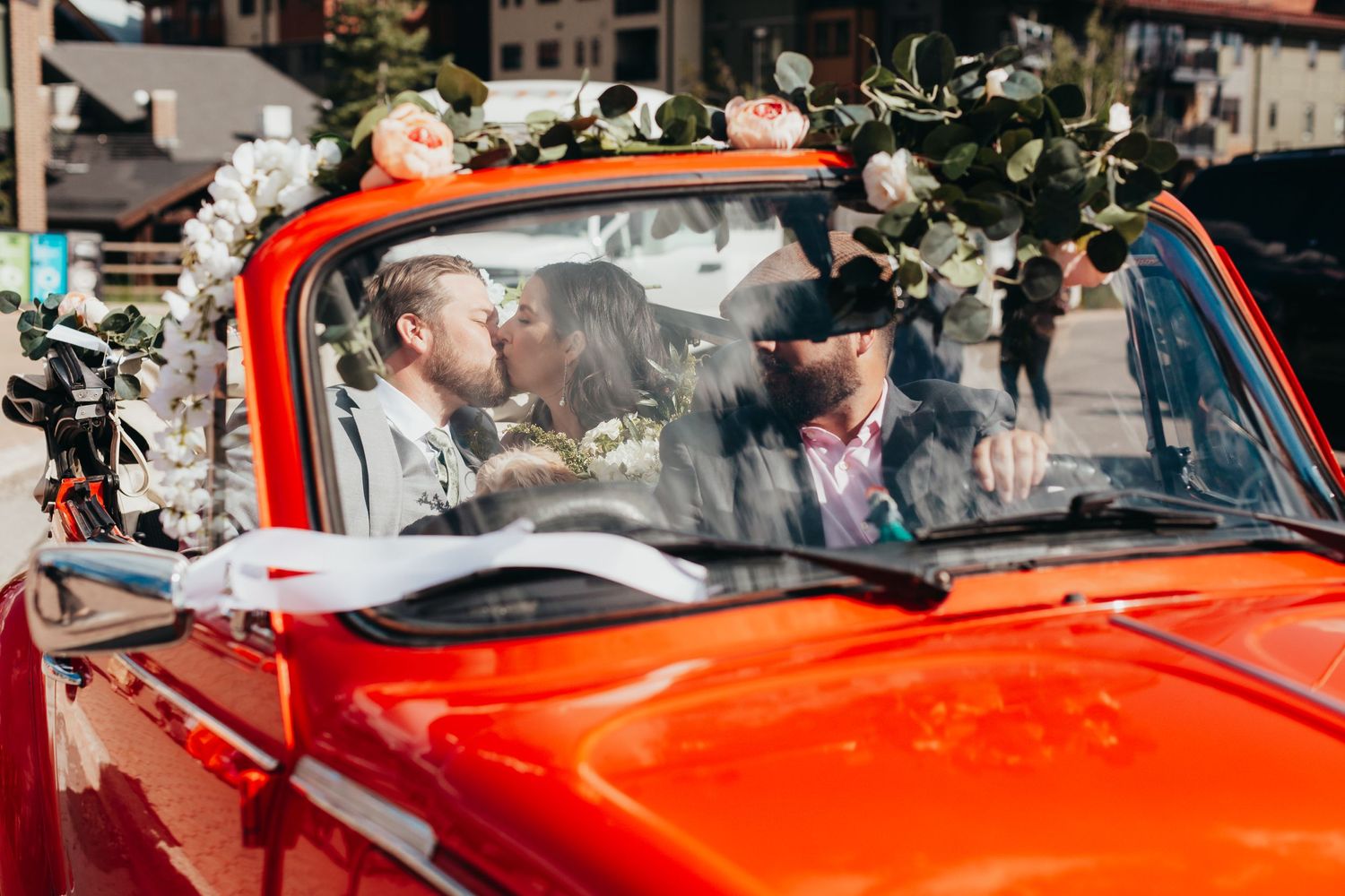 A bright red vintage convertible decorated with floral arrangements for a wedding.