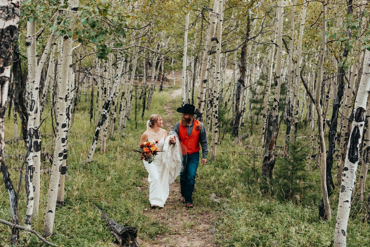 A couple walking through a serene aspen grove on a woodland path.