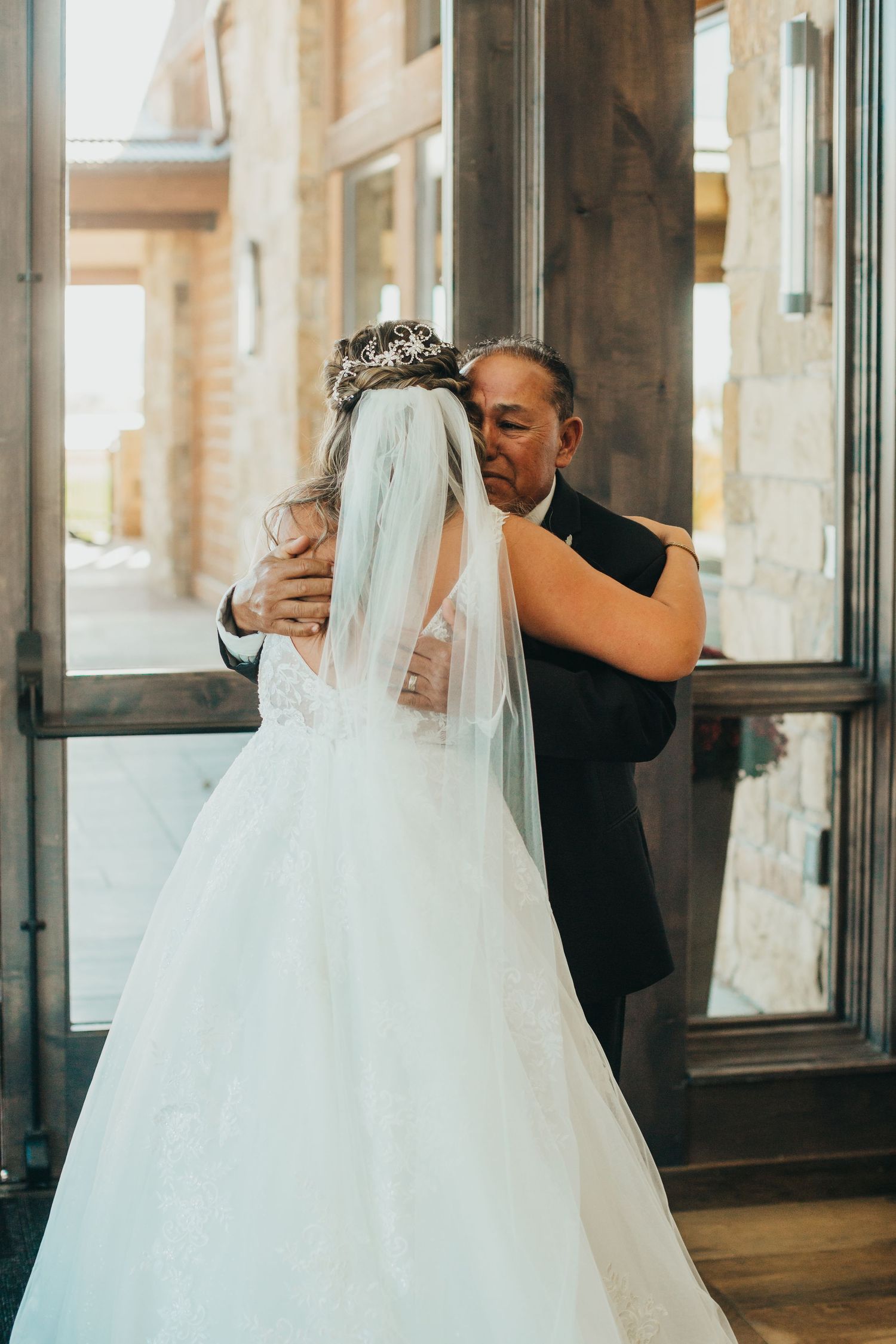 Tender moment captured during wedding as bride in white gown shares emotional embrace.