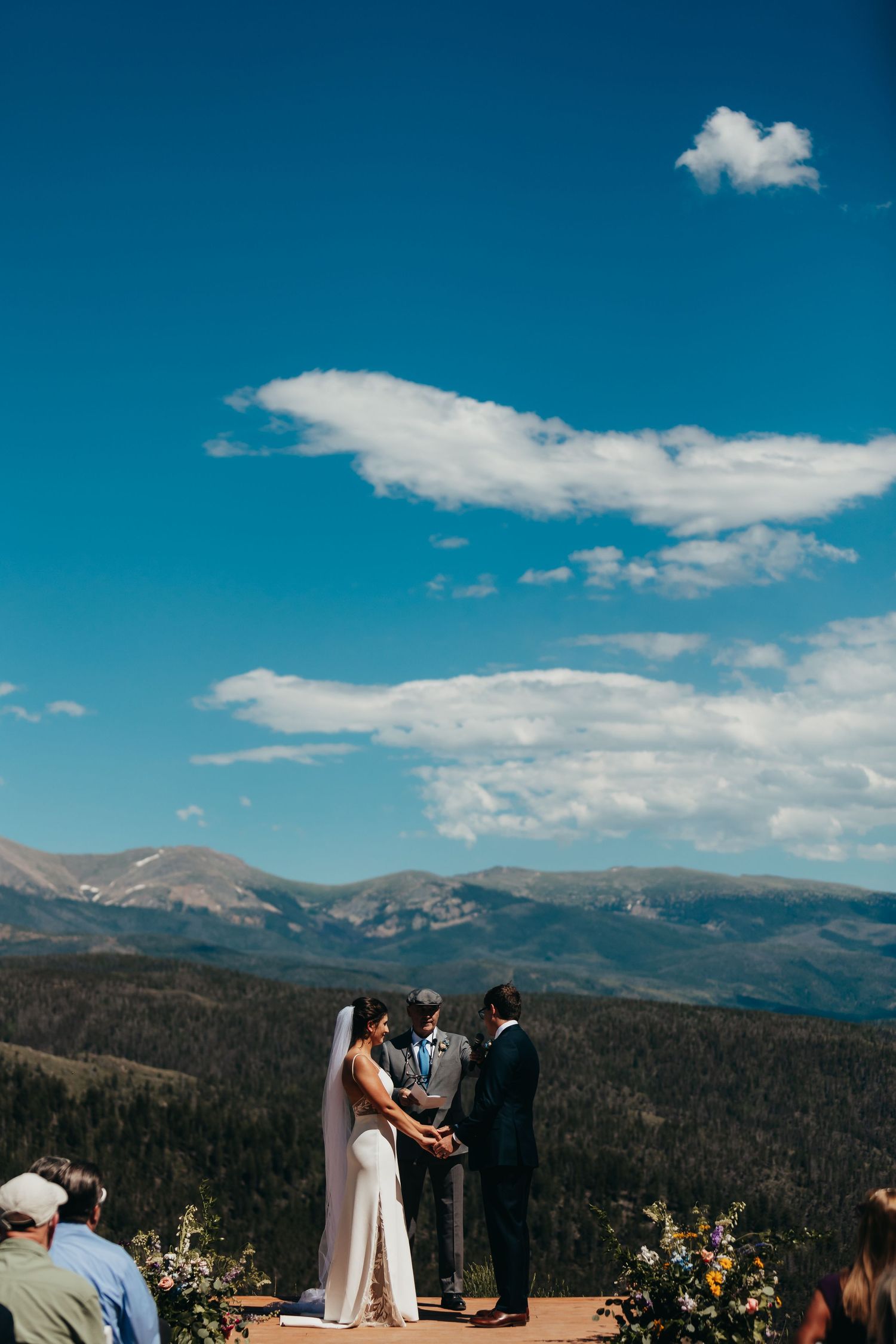 Mountain wedding ceremony with dramatic blue sky and mountain backdrop.