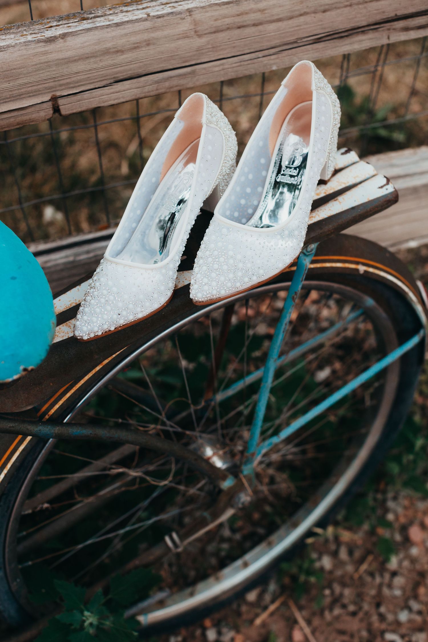 White lace wedding shoes with polka dots displayed on a vintage bicycle.