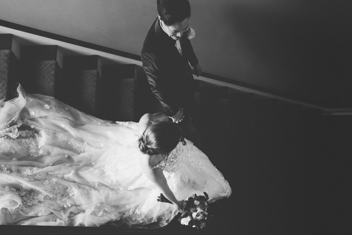 A black and white wedding photo showing formal attire and flowing dress details.