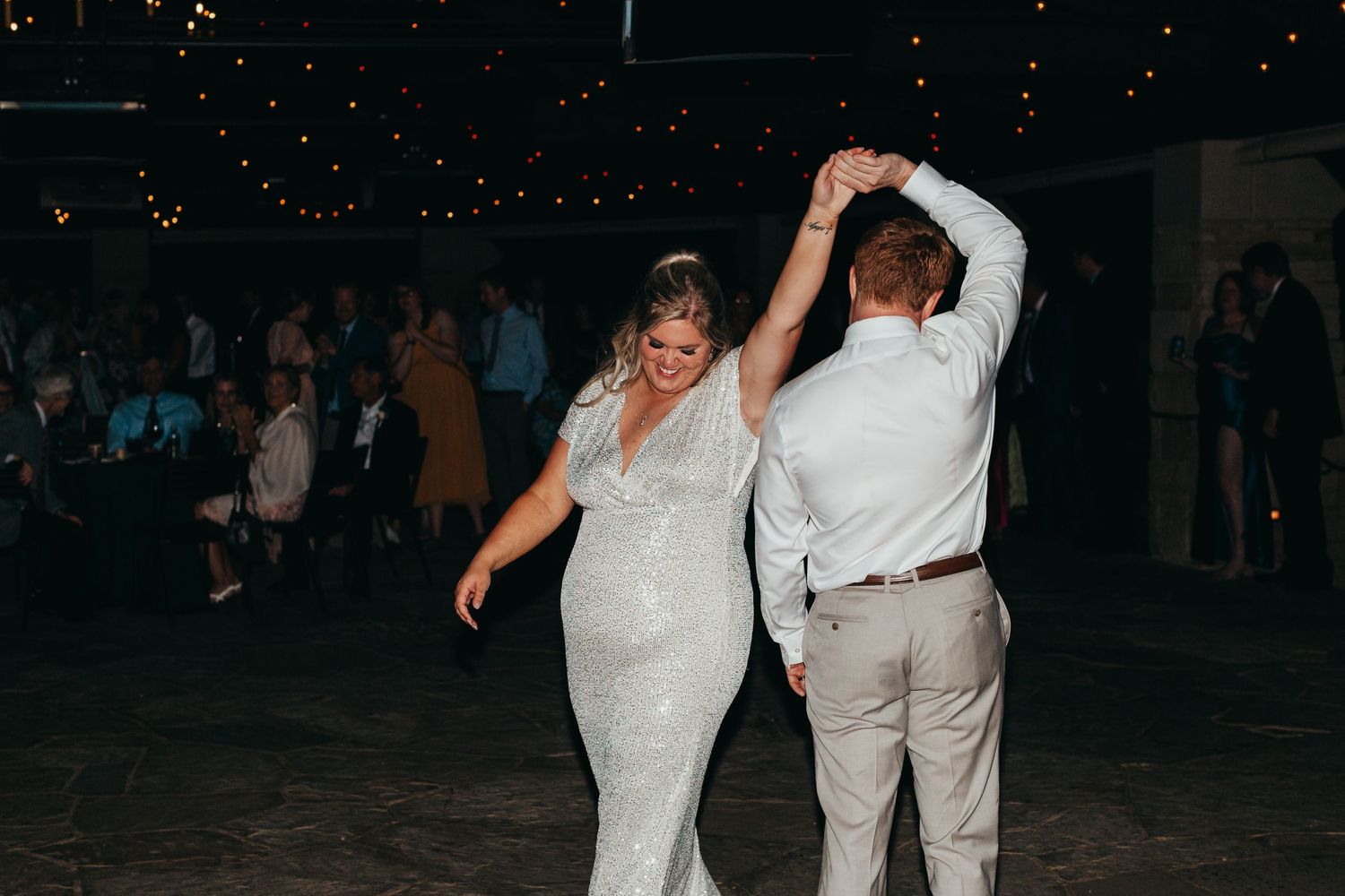 Newlyweds dancing together on dark dance floor during wedding reception.