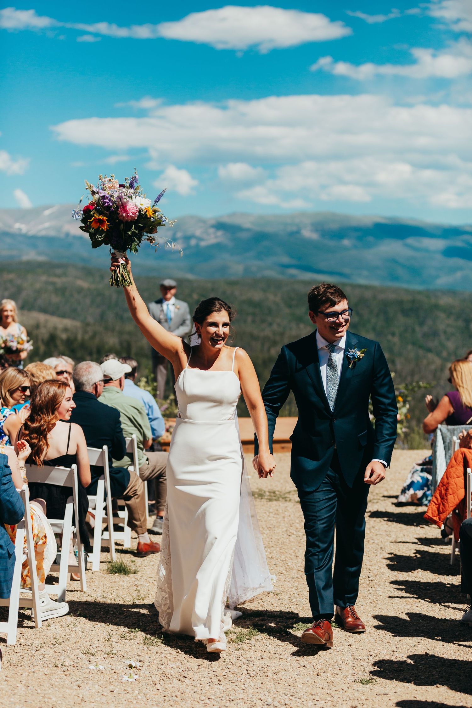 Newlyweds walking down the aisle at a mountain-top wedding celebration.