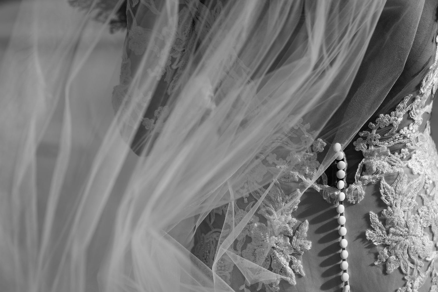 Close-up detail of intricate beading and lace on bridal veil in black and white.