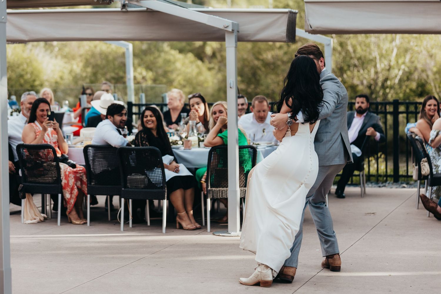 Couple performs romantic dance move while wedding guests watch from their seats.