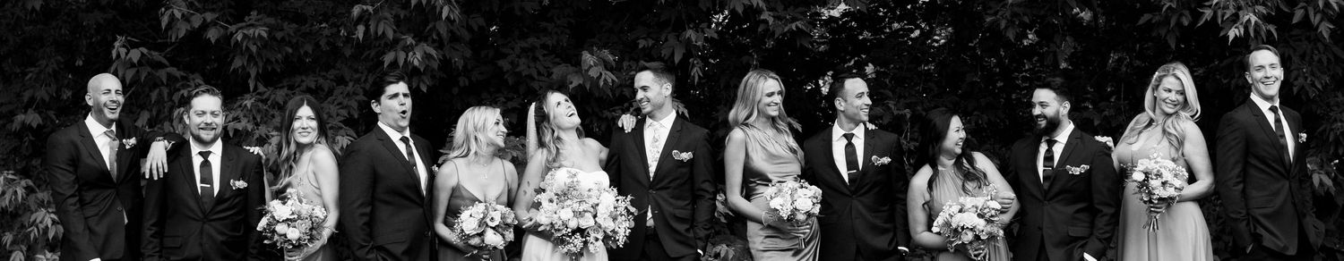 Black and white panorama of wedding party lineup at outdoor ceremony.