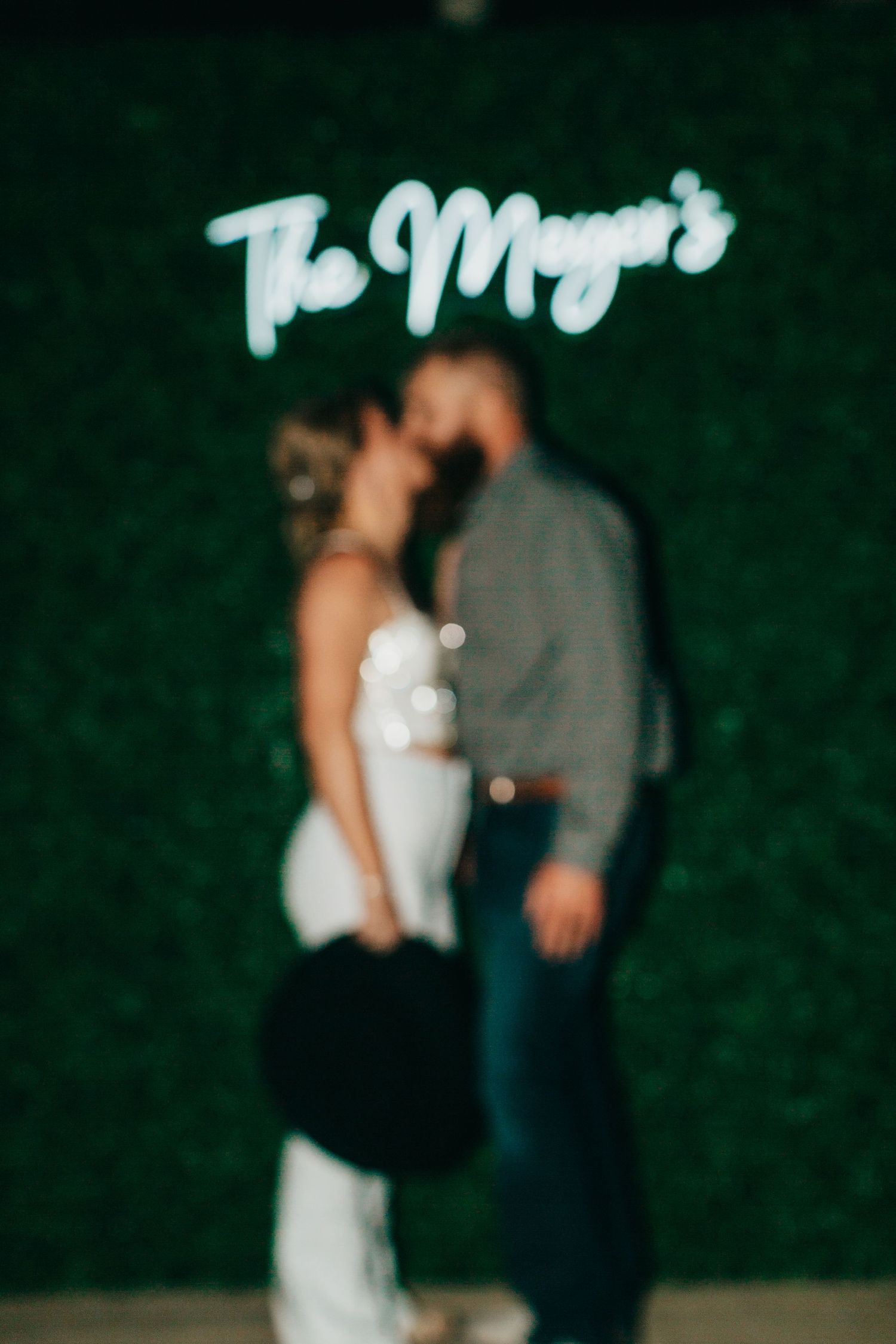 A silhouetted couple in front of an illuminated 'The Meyer's' neon sign.