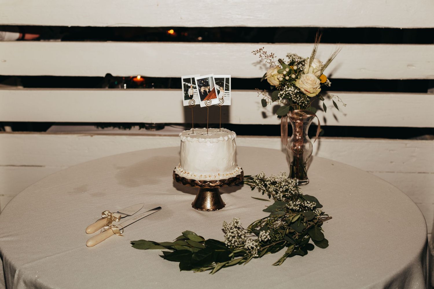 Elegant wedding cake and floral arrangement displayed on round table.