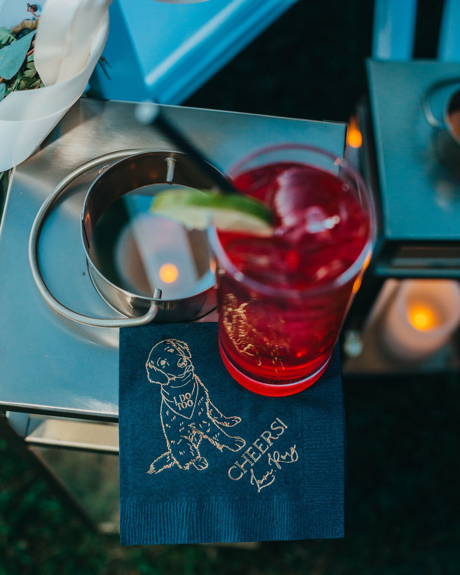 Wedding cocktail and rings on a blue napkin with custom illustration.