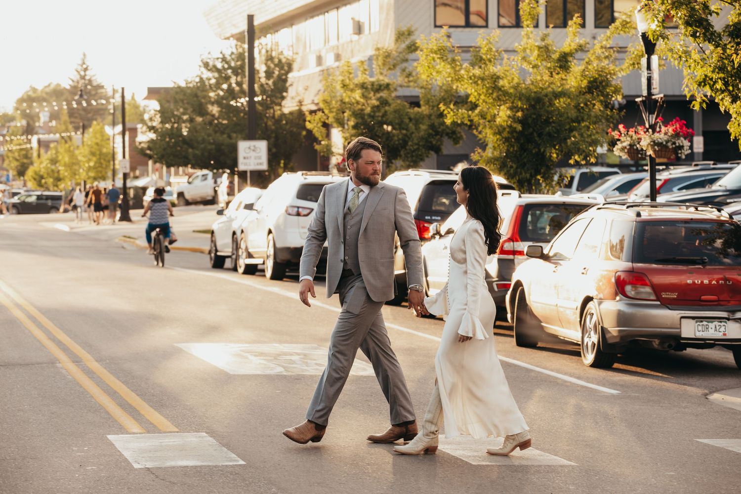 Couple walks down a sunny street after their wedding ceremony.