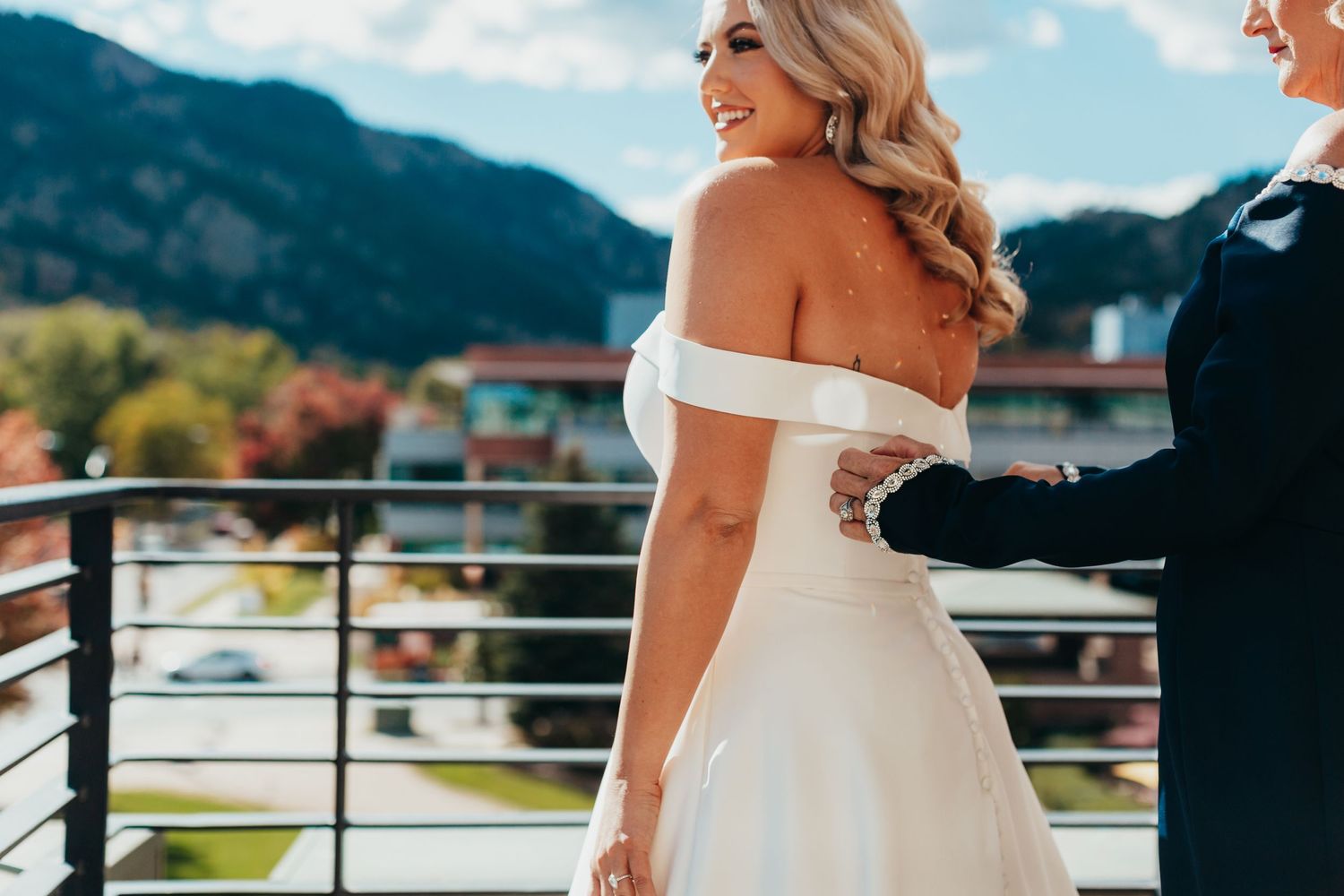 A stunning off-shoulder wedding dress detail against mountain scenery.