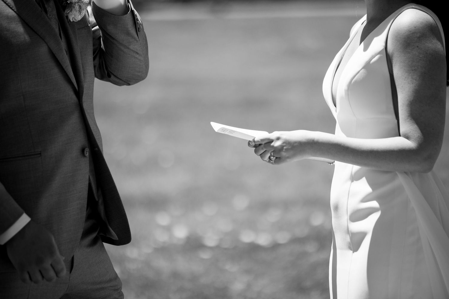Black and white photo of couple exchanging vows or notes during ceremony.