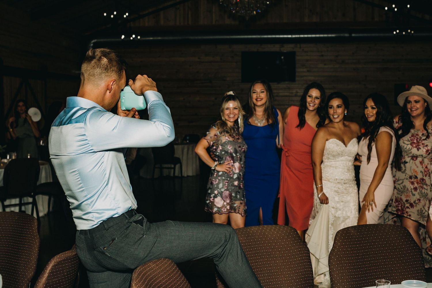 A celebratory dance scene inside a rustic barn venue with colorfully dressed guests.