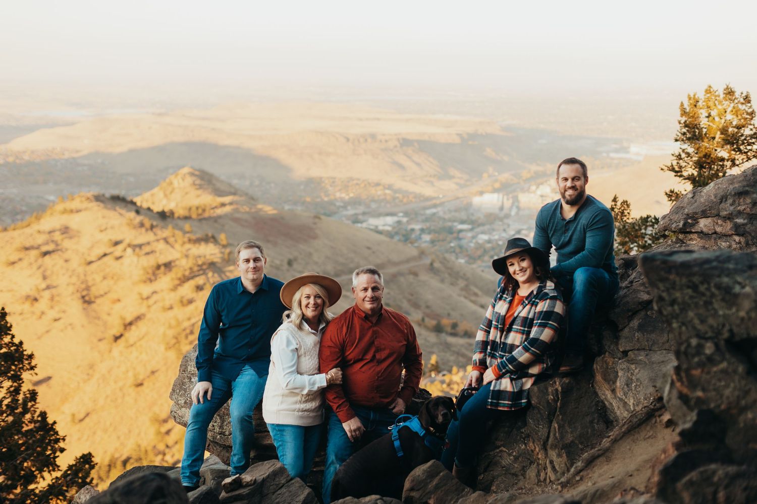 Group poses together on mountain overlook with scenic valley views below.