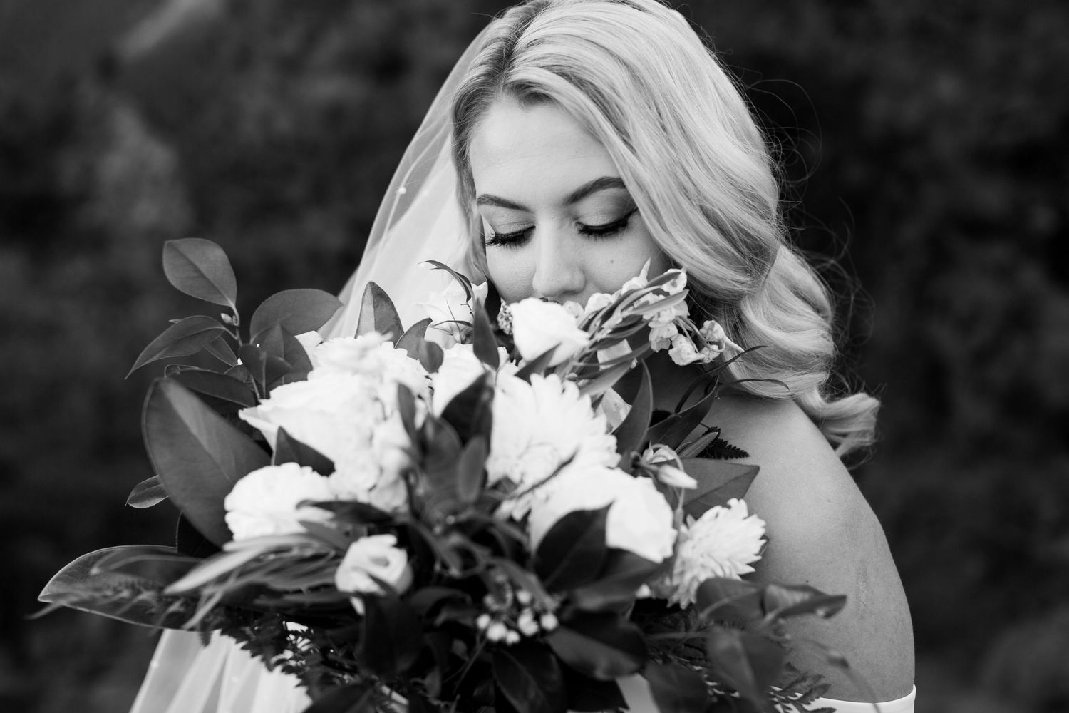 A black and white portrait of a bride holding a beautiful bouquet of white flowers.