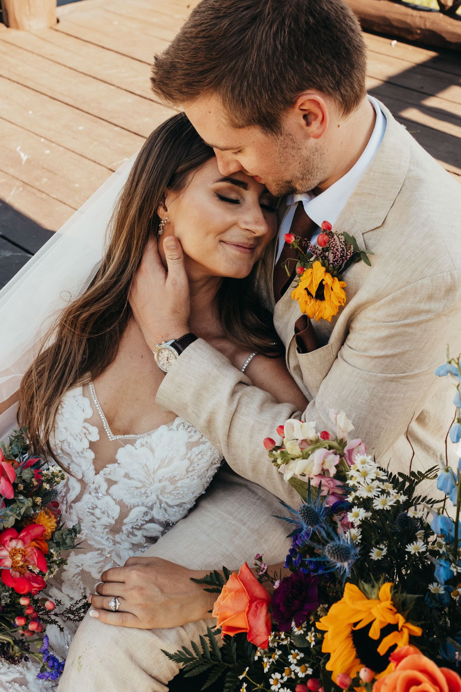 Intimate wedding portrait with vibrant sunflower and rose bouquet details.