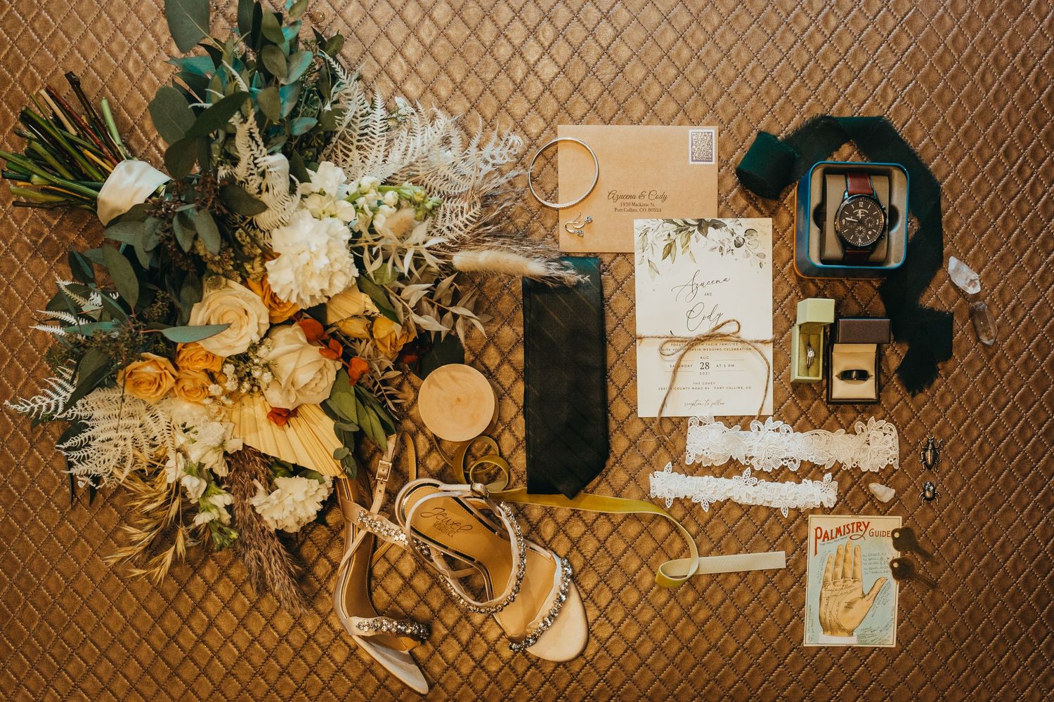 Wedding details flatlay with florals, invitations, and vintage camera on textured background.