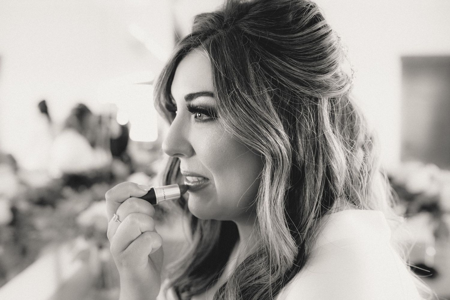 A close-up black and white portrait showing elegant bridal makeup and hairstyling.