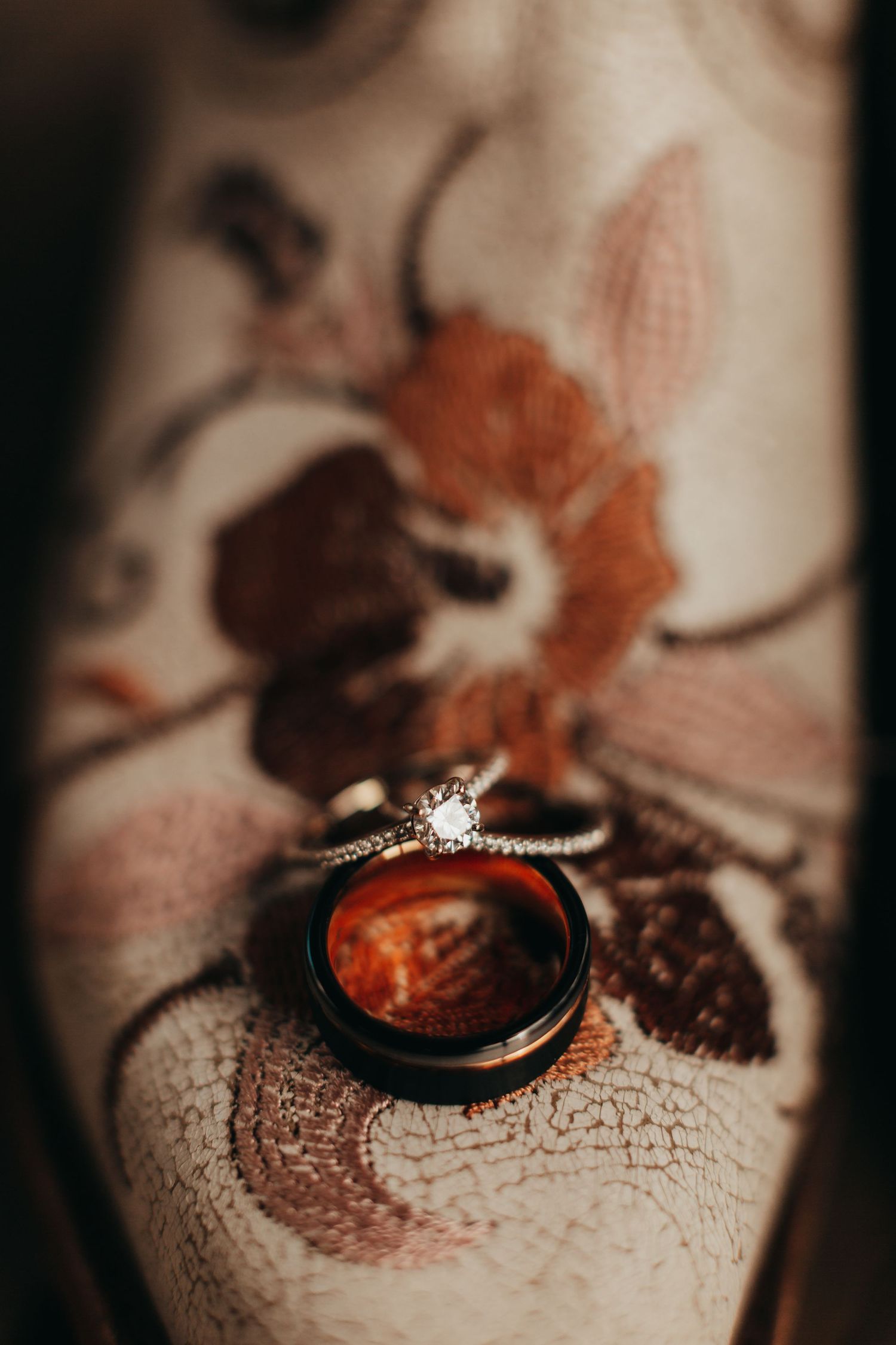 Wedding rings placed on vintage paper with floral designs in soft focus.
