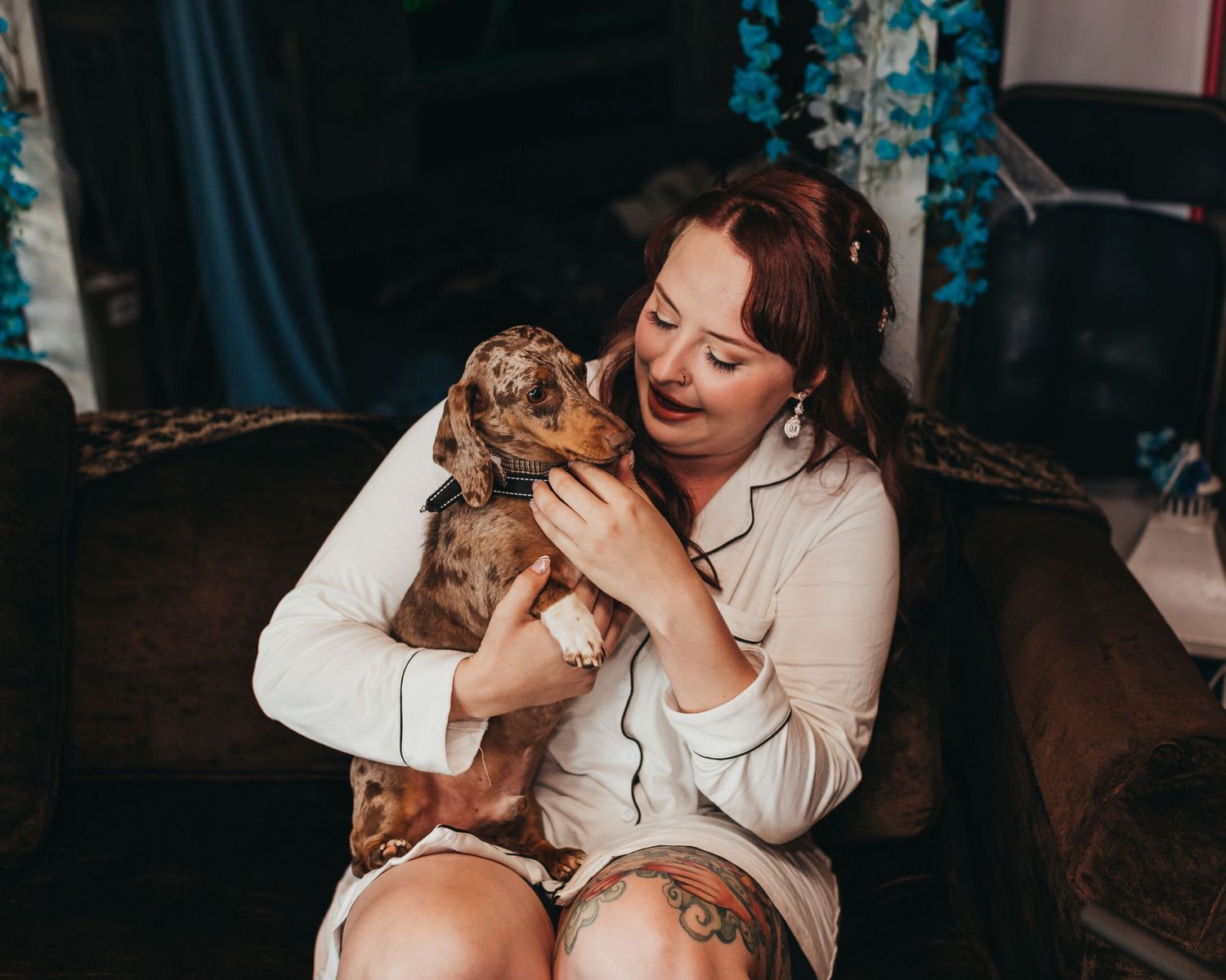 Woman in white sweater cuddles small puppy while sitting indoors.
